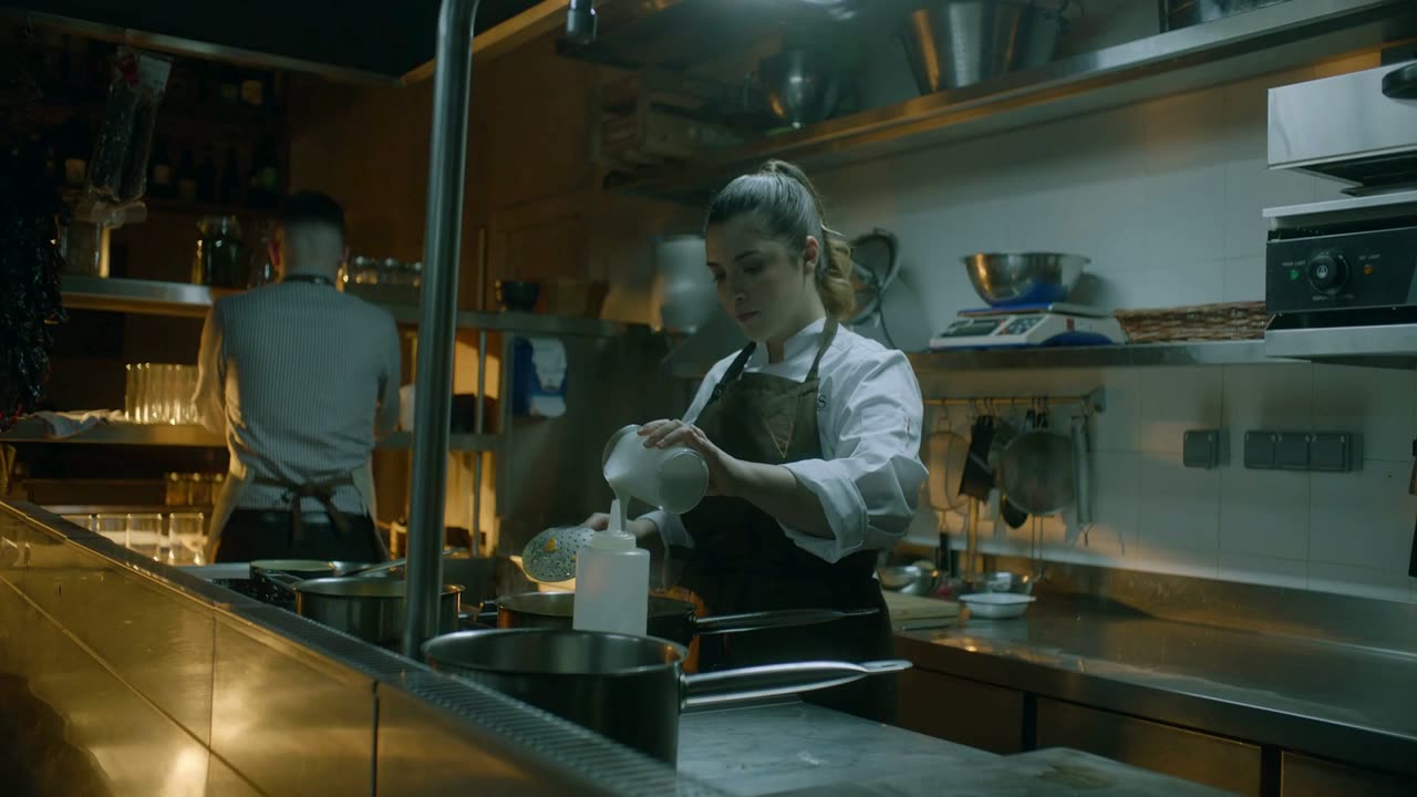 A chef plating in a professional kitchen during service