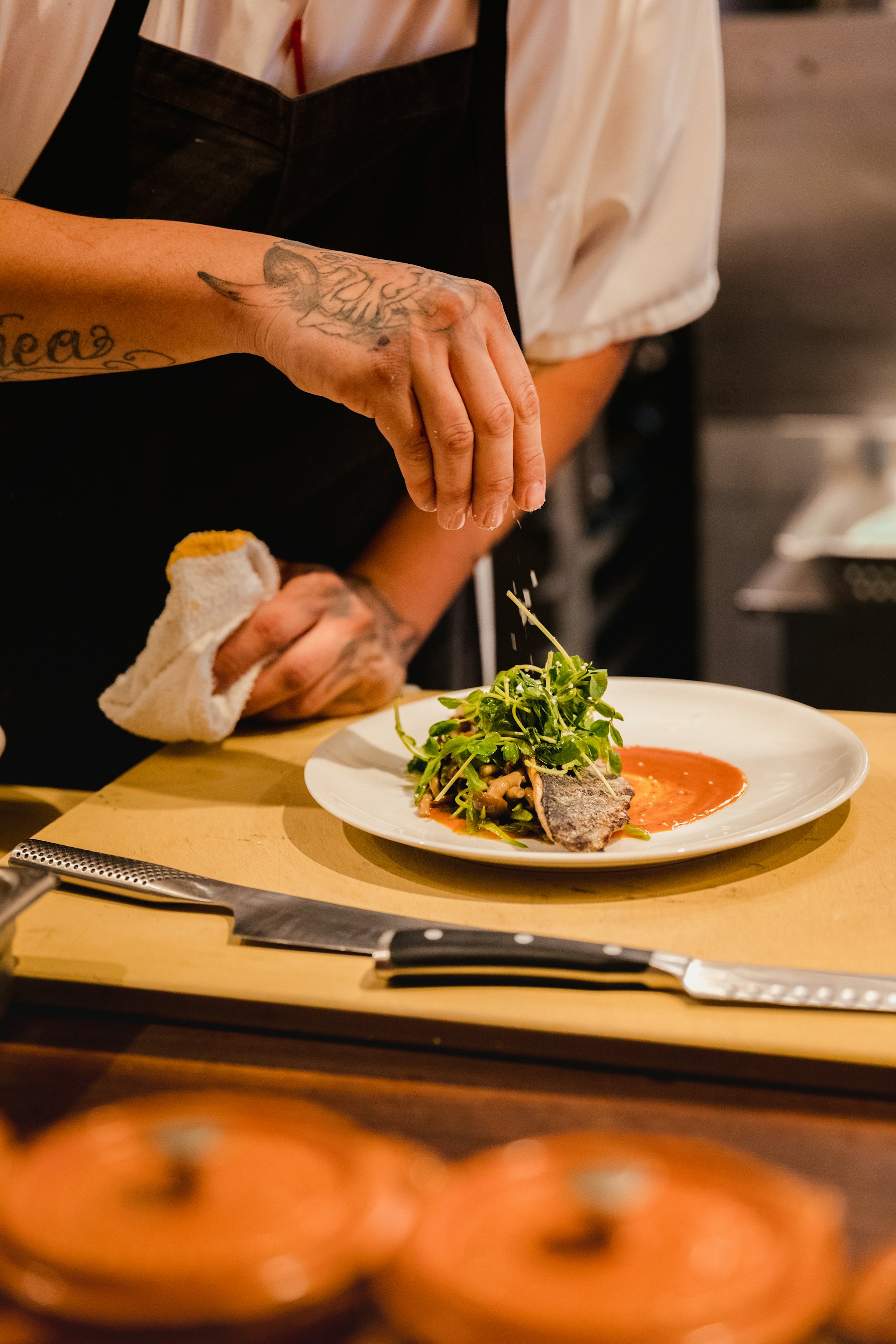 A chef finishing a plated dish by hand