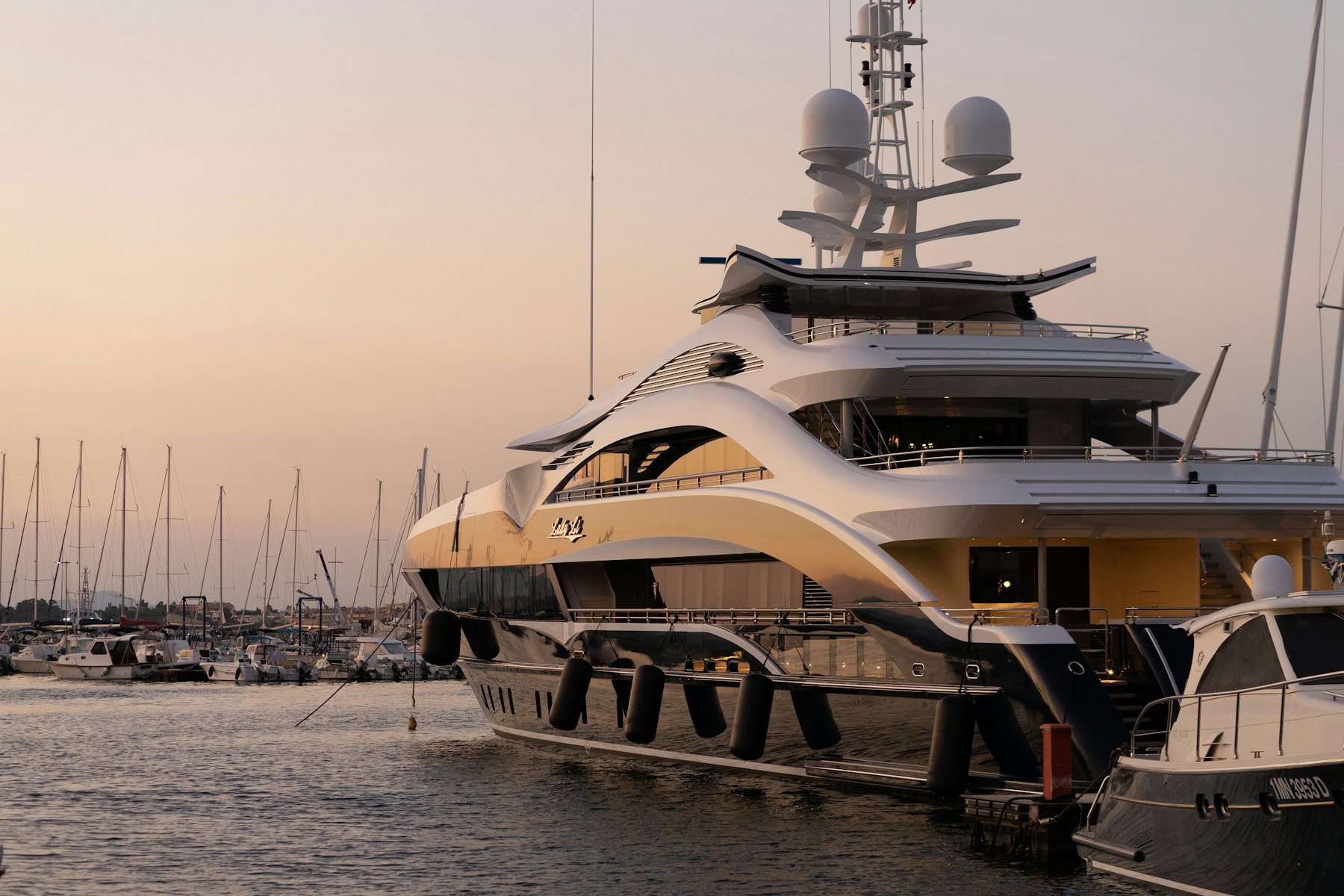 A superyacht moored in a marina at dusk
